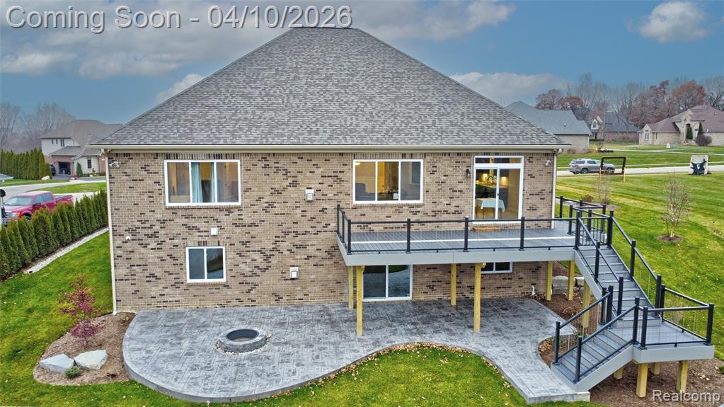 Back of property featuring a patio area, brick siding, a deck, and a yard