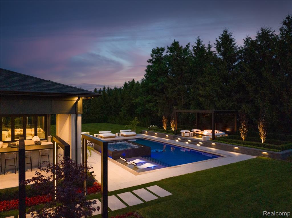 View of swimming pool with a yard, a patio area, a pool with connected hot tub, and exterior kitchen