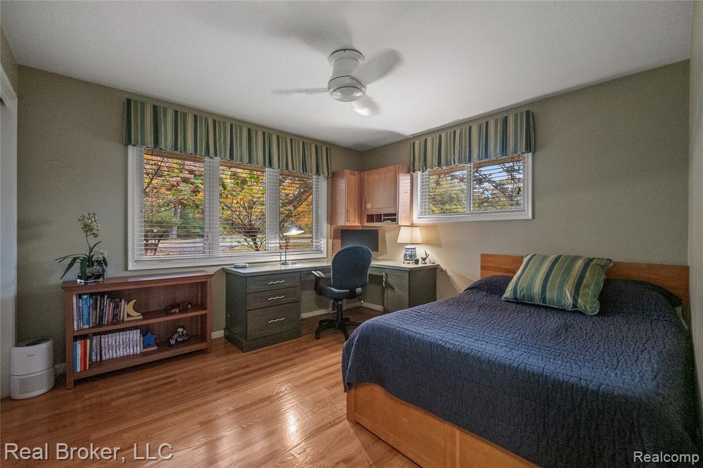 Bedroom featuring light wood-style floors, ceiling fan, and an office area