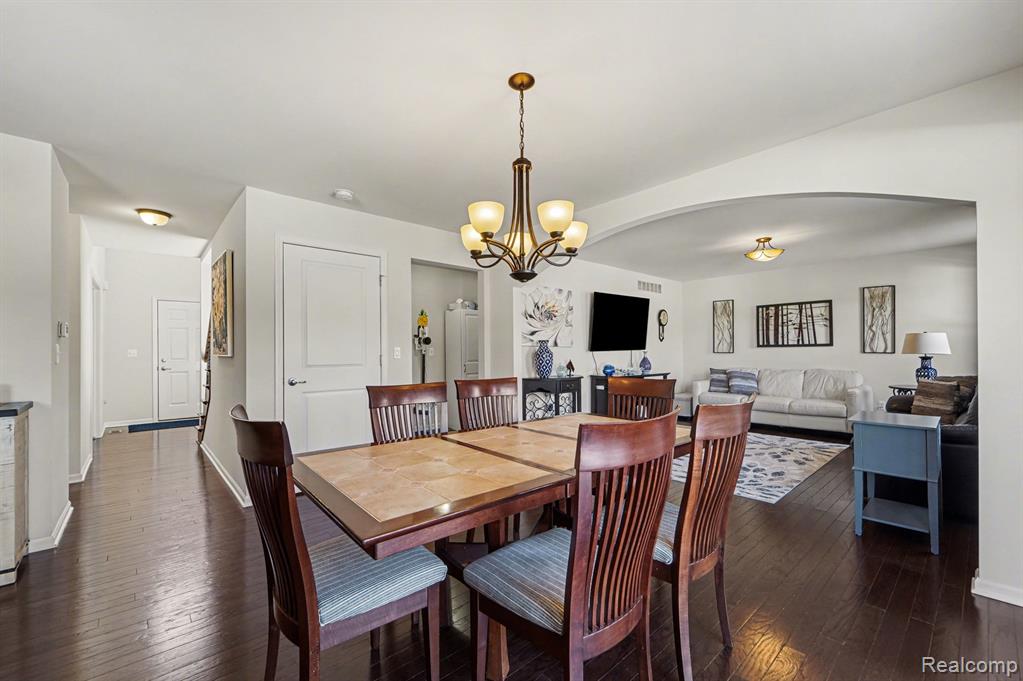 Dining room with dark wood-type flooring, hanging lights, and arched walkways