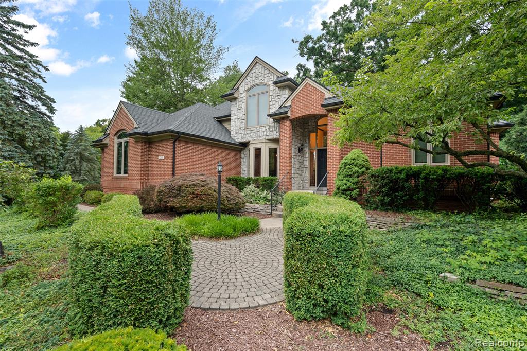 View of front of property featuring stone siding, brick siding, and a shingled roof