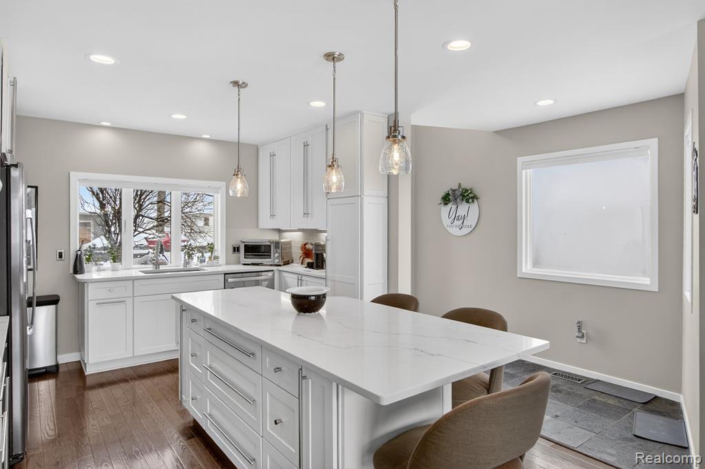 Kitchen featuring a breakfast bar area, light stone countertops, a center island, decorative light fixtures, and recessed lighting