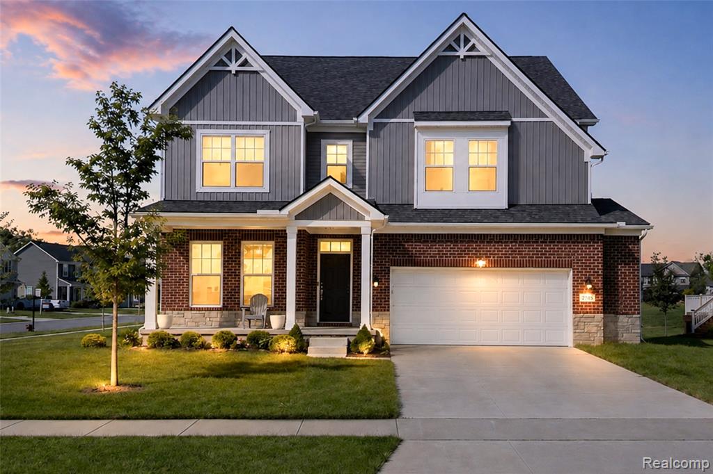 Two-story Colonial home featuring a brick and vertical siding exterior with gabled rooflines and decorative cross-bracing in the gable peaks
