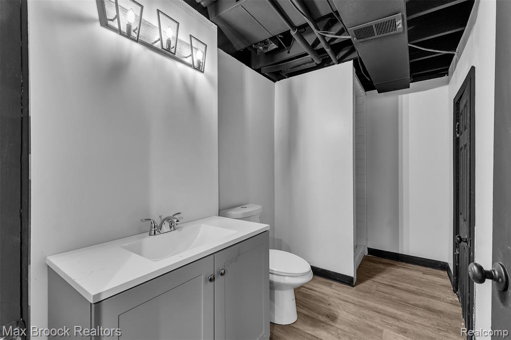 Full bath featuring vanity, light wood-style floors, and a shower stall