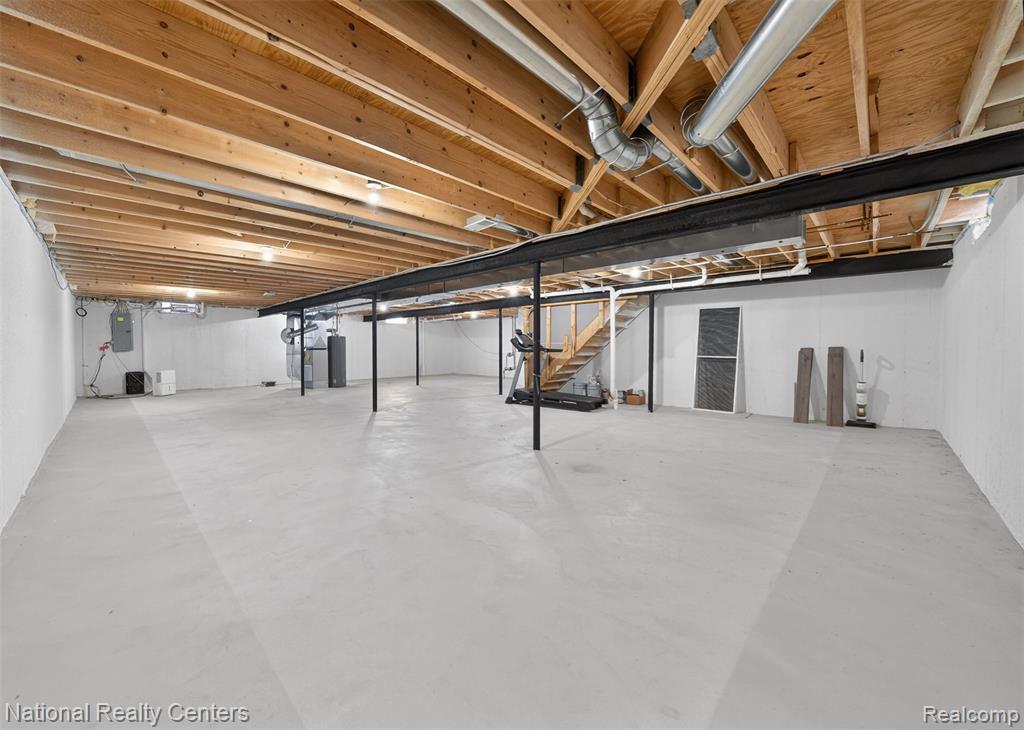 Unfinished basement featuring heating unit and electric panel