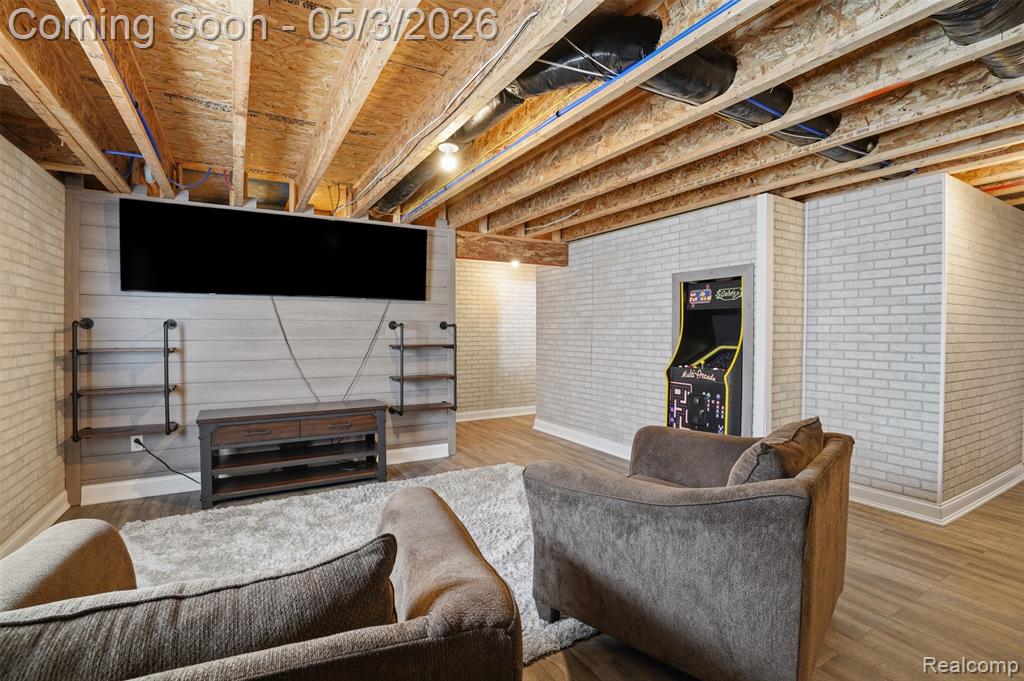 Finished lower level room with brick wall and wood finished floors