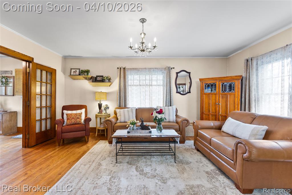 Living area featuring light wood-type flooring, a chandelier, and ornamental molding