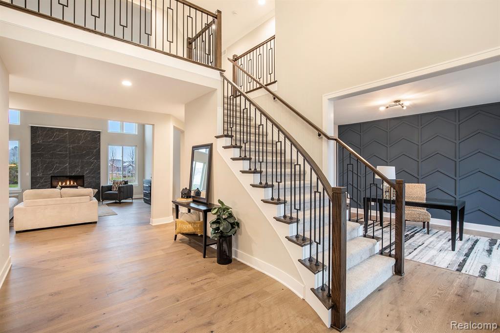 Stairway featuring a premium fireplace, an accent wall, wood finished floors, a high ceiling, and recessed lighting