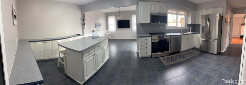 Kitchen with stainless steel appliances, white cabinetry, a center island, and pendant lighting