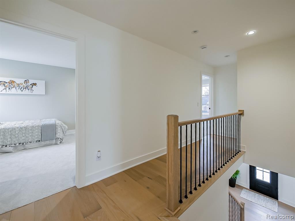 Hallway featuring an upstairs landing, wood finished floors, and recessed lighting