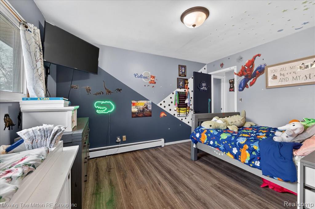 Bedroom with a baseboard radiator and dark wood-type flooring
