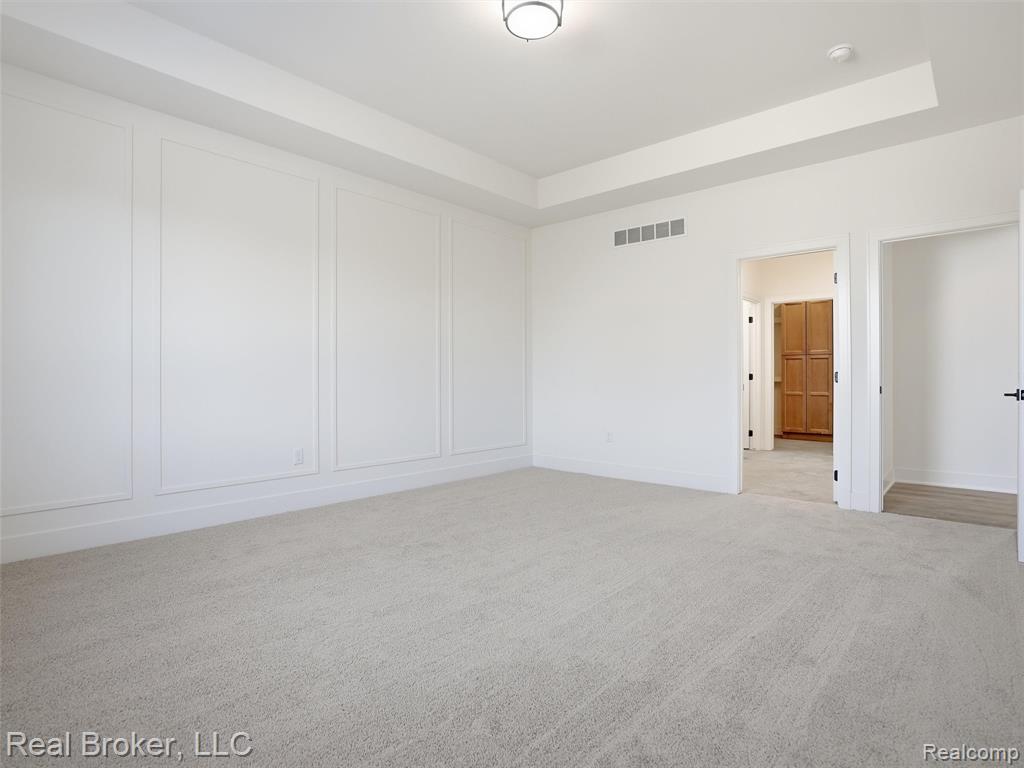 Unfurnished bedroom featuring light colored carpet and a tray ceiling