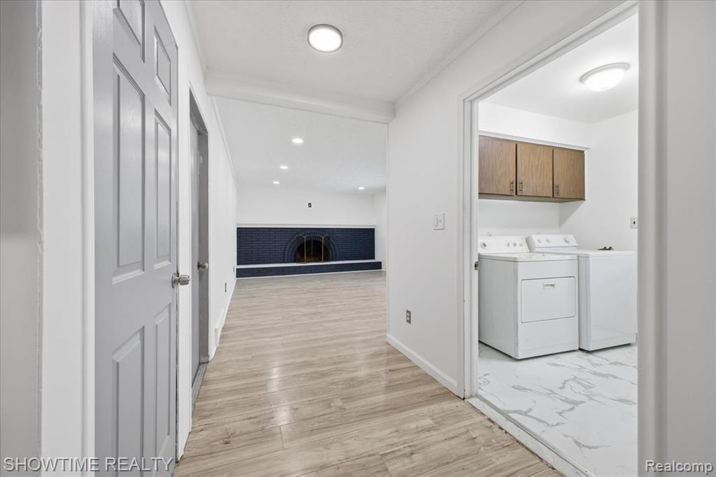 Laundry room with washing machine and clothes dryer, recessed lighting, light wood-type flooring, and cabinet space