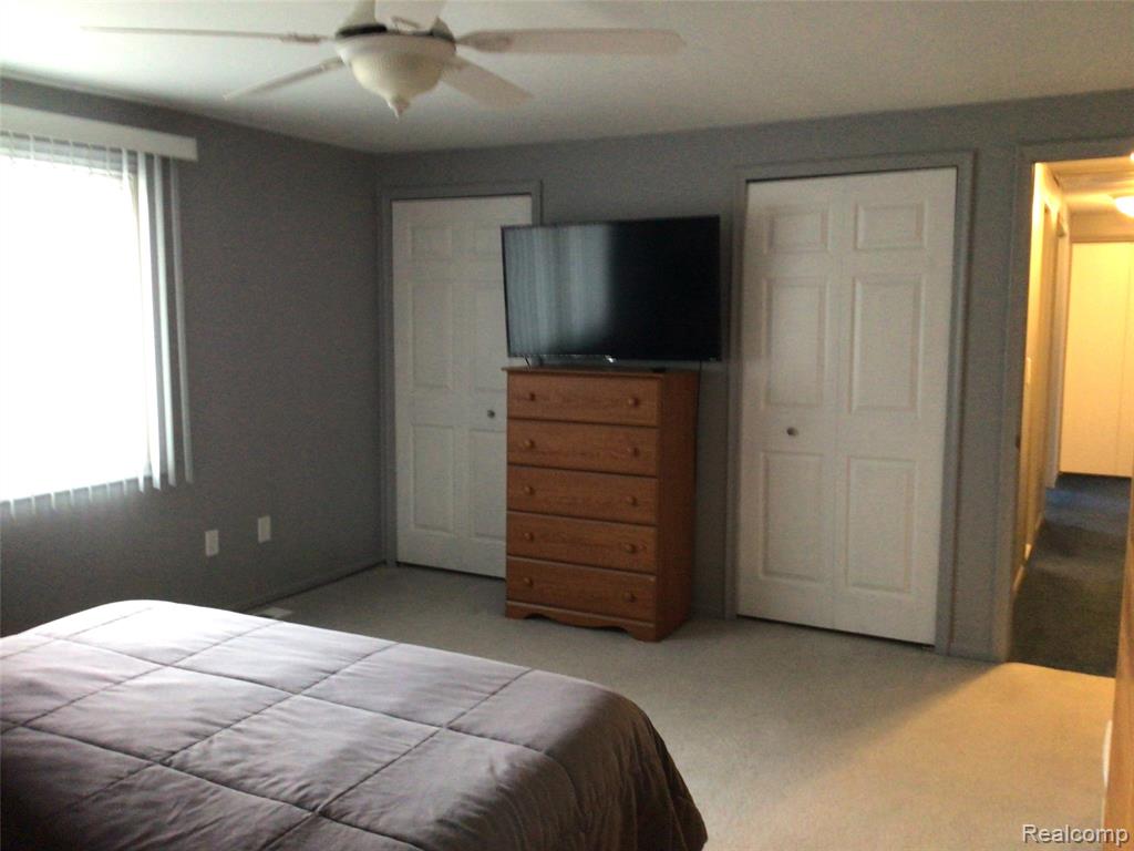 Bedroom with light colored carpet and a ceiling fan