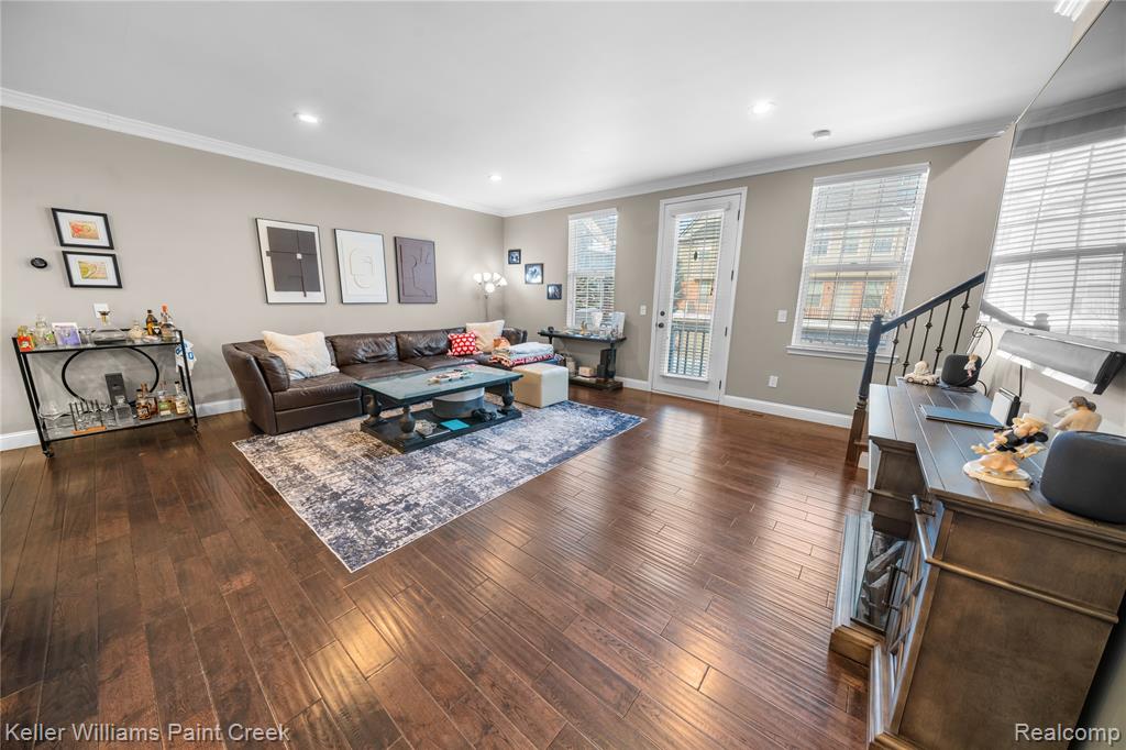 Living room with dark wood-style flooring, crown molding, and recessed lighting