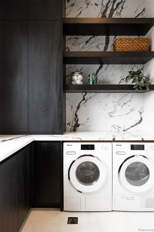 Laundry area with washing machine and clothes dryer and light tile patterned floors