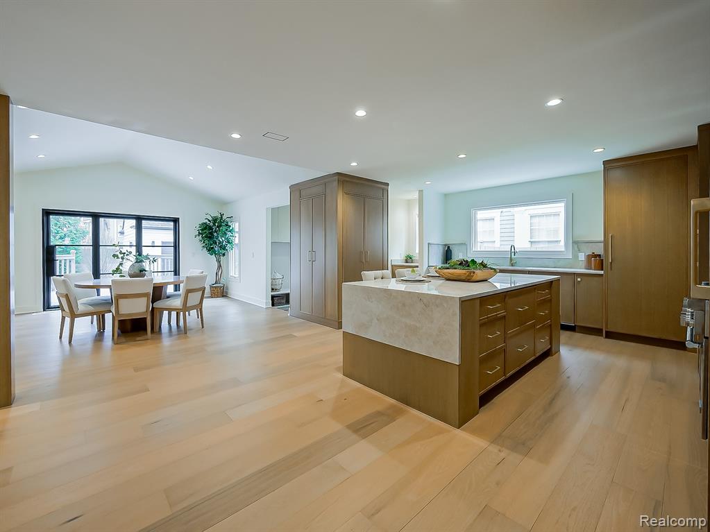 Kitchen featuring lofted ceiling, light wood finished floors, a center island, light stone counters, and recessed lighting