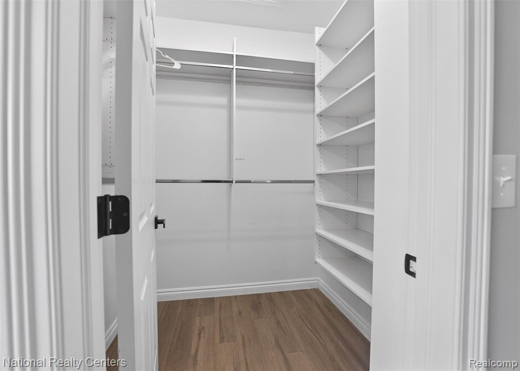 Walk in closet with dark wood-style floors