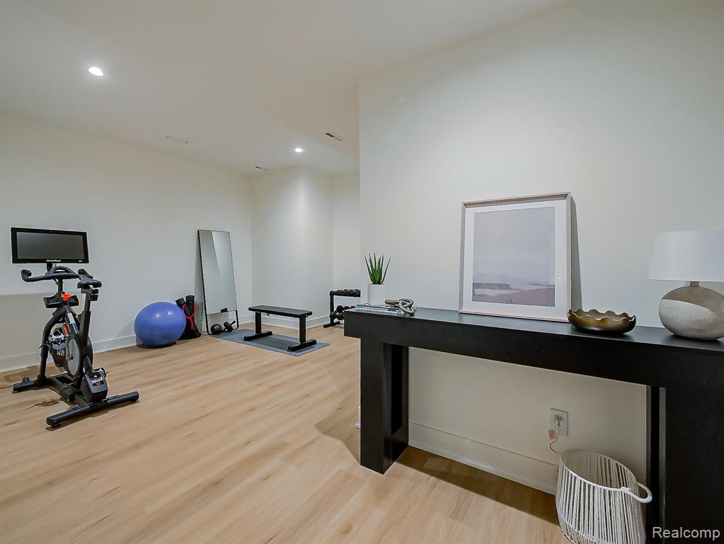 Exercise area with light wood-type flooring and recessed lighting