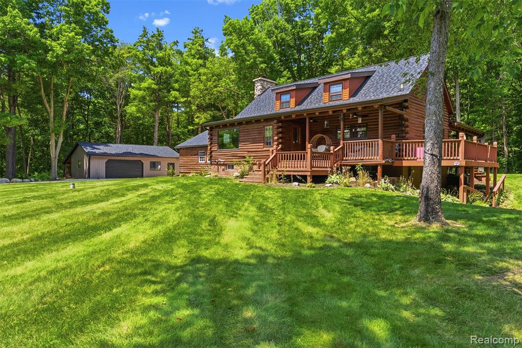 Log-sided home featuring an expansive front lawn and a covered porch