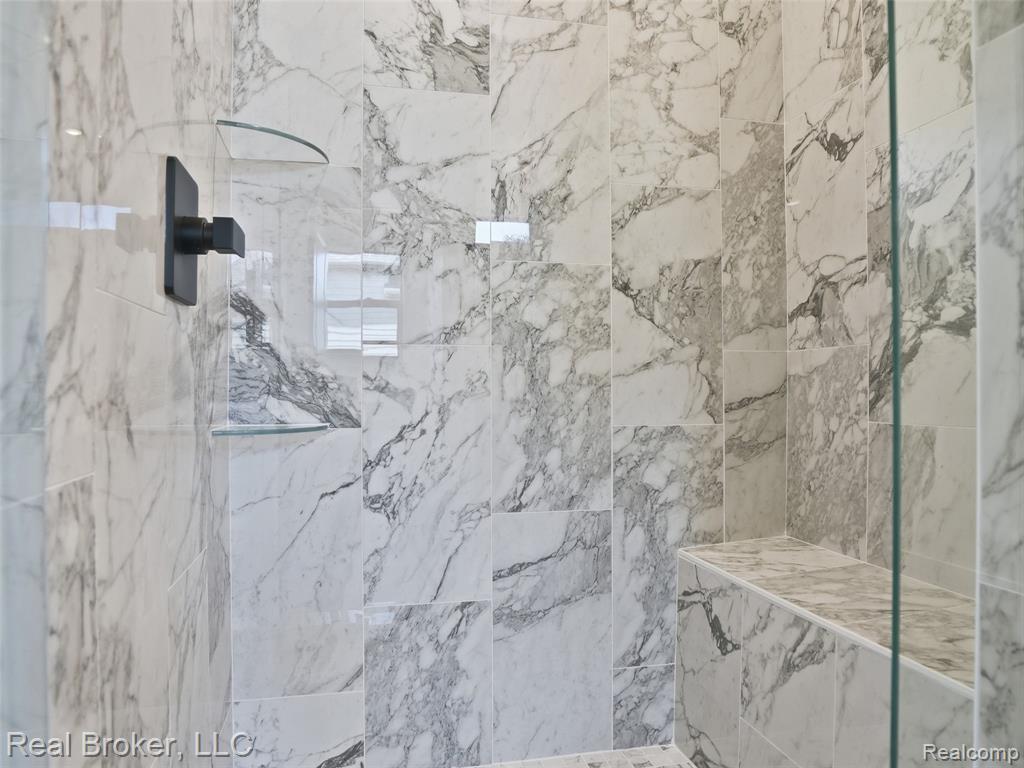 Full bath with a marble finish shower