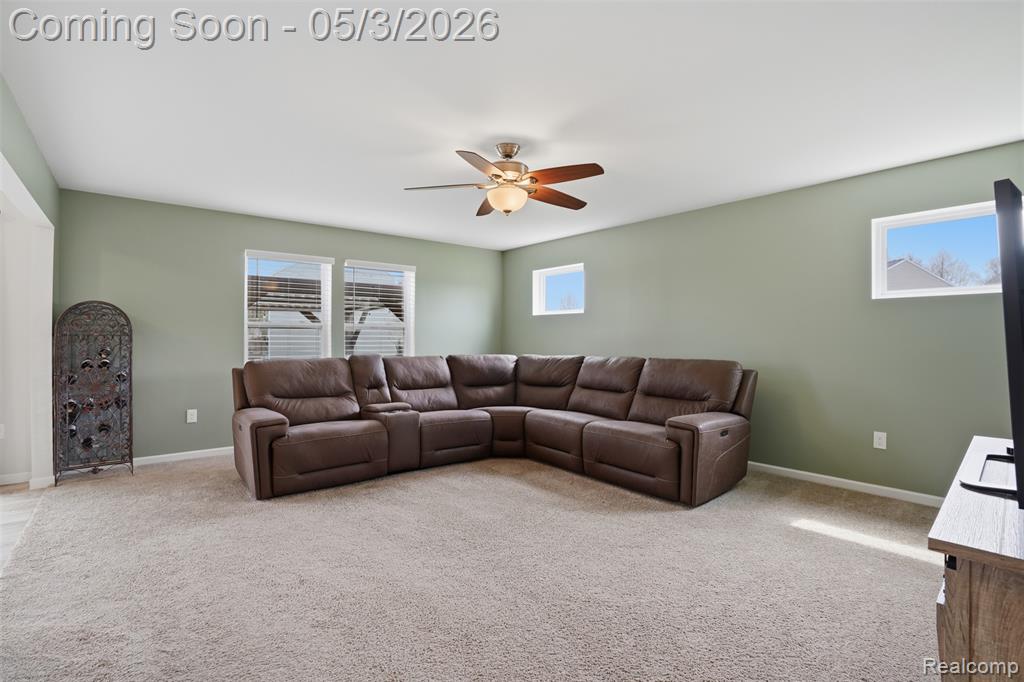 Living room with ceiling fan, light colored carpet, and healthy amount of natural light