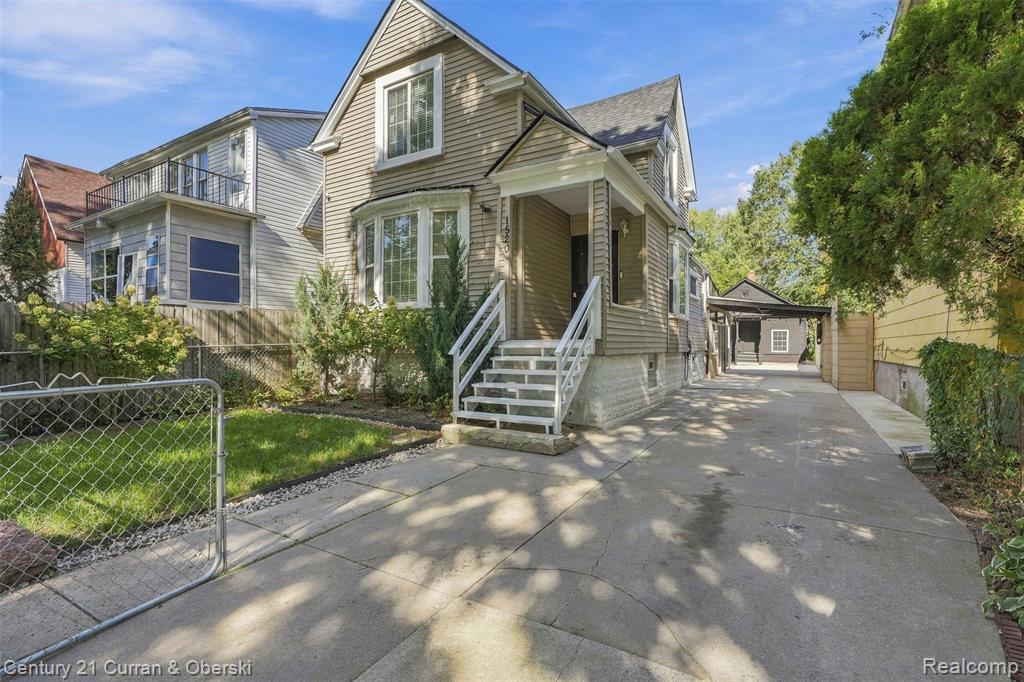 Siding exterior with a covered porch, bay window, concrete driveway, and detached carport