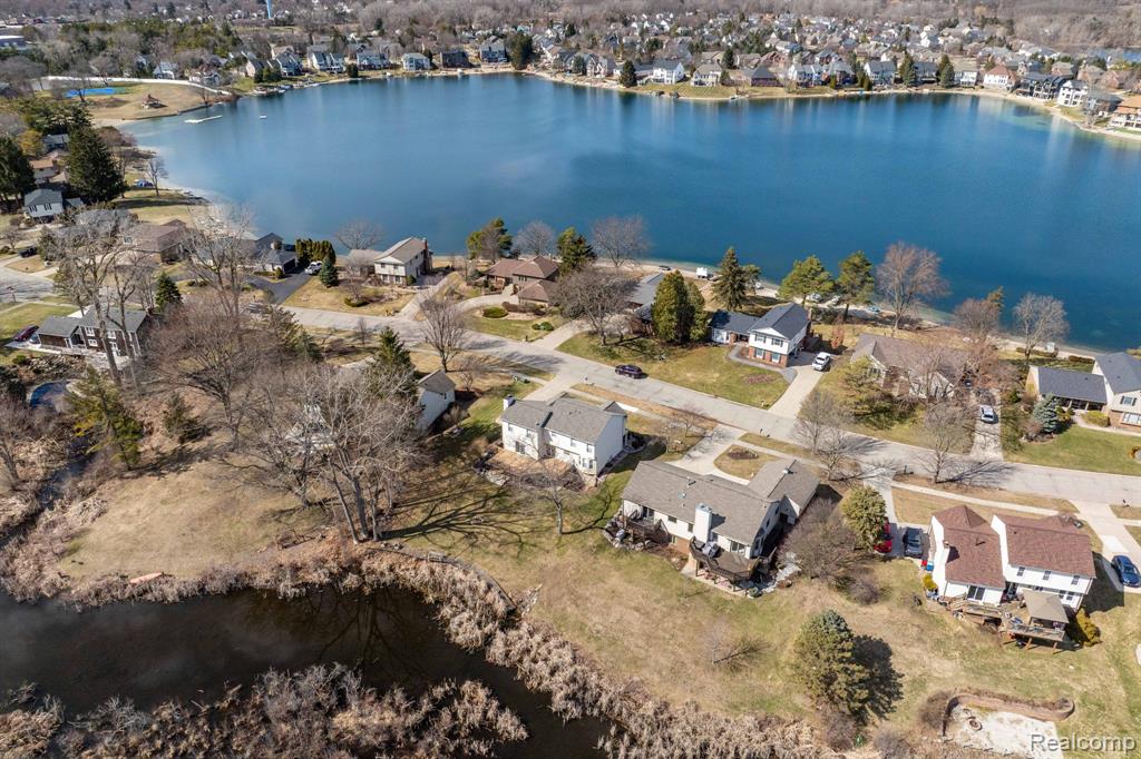 Aerial view of property and surrounding area featuring a nearby body of water and nearby suburban area