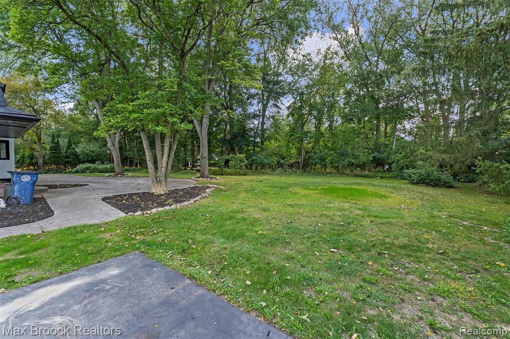 View of green lawn featuring a patio and view of wooded area
