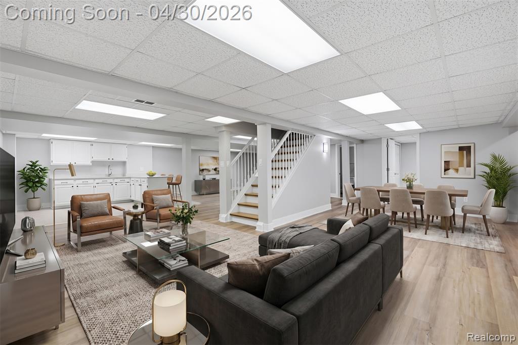 Lower Level Living area featuring laminate flooring and a paneled drop ceiling open to kitchenette