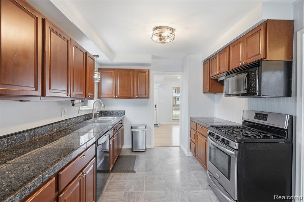Kitchen featuring stainless steel appliances, tile counters, and wood finish cabinetry