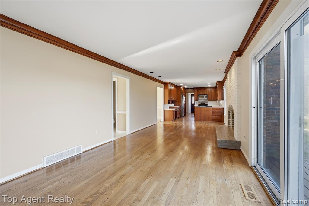Unfurnished living room featuring ornamental molding, a brick fireplace, recessed lighting, wood finished floors, and plenty of natural light