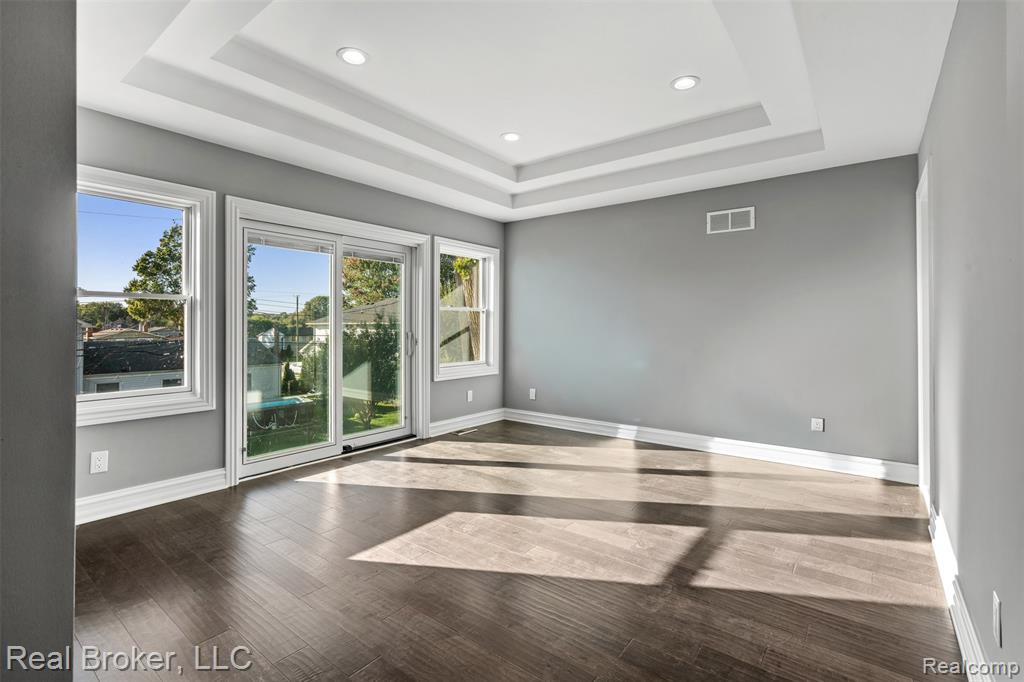Unfurnished room featuring wood finished floors, recessed lighting, and a raised ceiling
