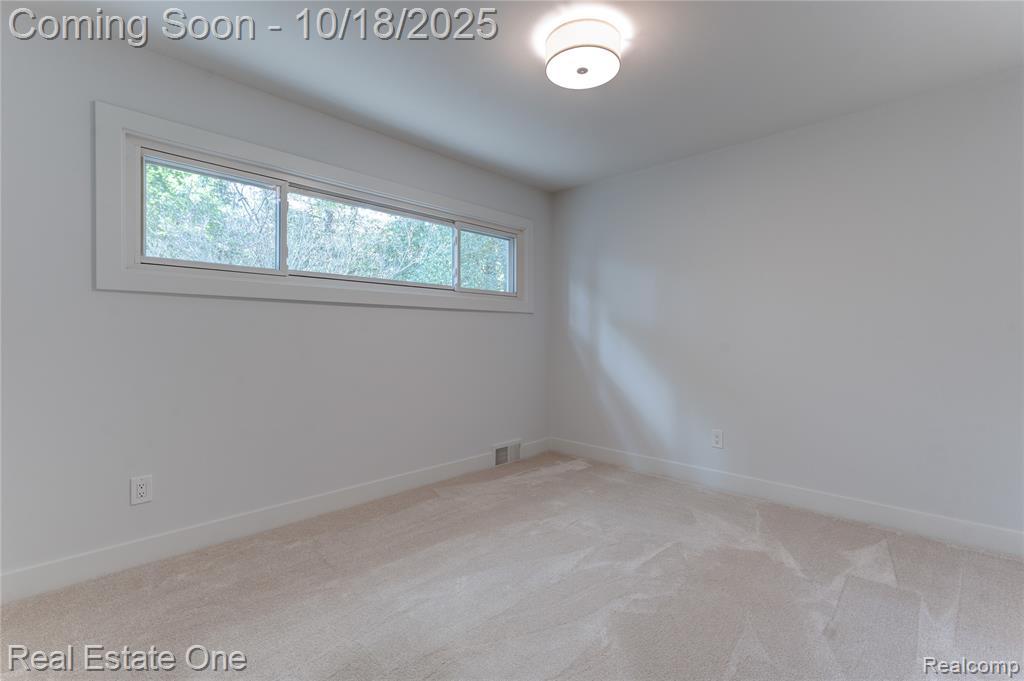 Empty room with light colored carpet and baseboards