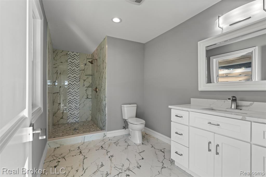 Bathroom featuring a marble finish shower, vanity, light marble finish floors, recessed lighting, and a wall unit AC