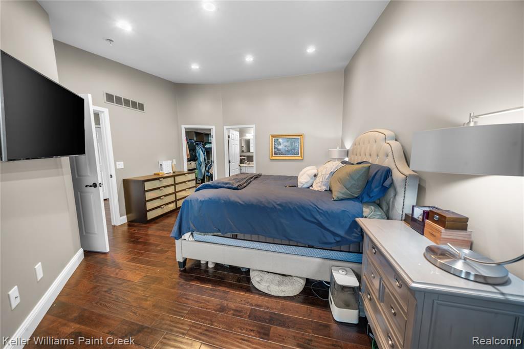 Bedroom featuring a spacious closet and dark wood-style floors