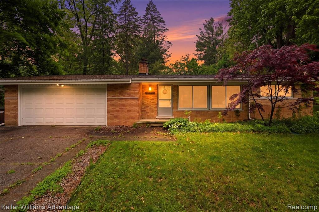 Brick ranch-style residence featuring an attached garage, front entry, and multiple windows across the facade