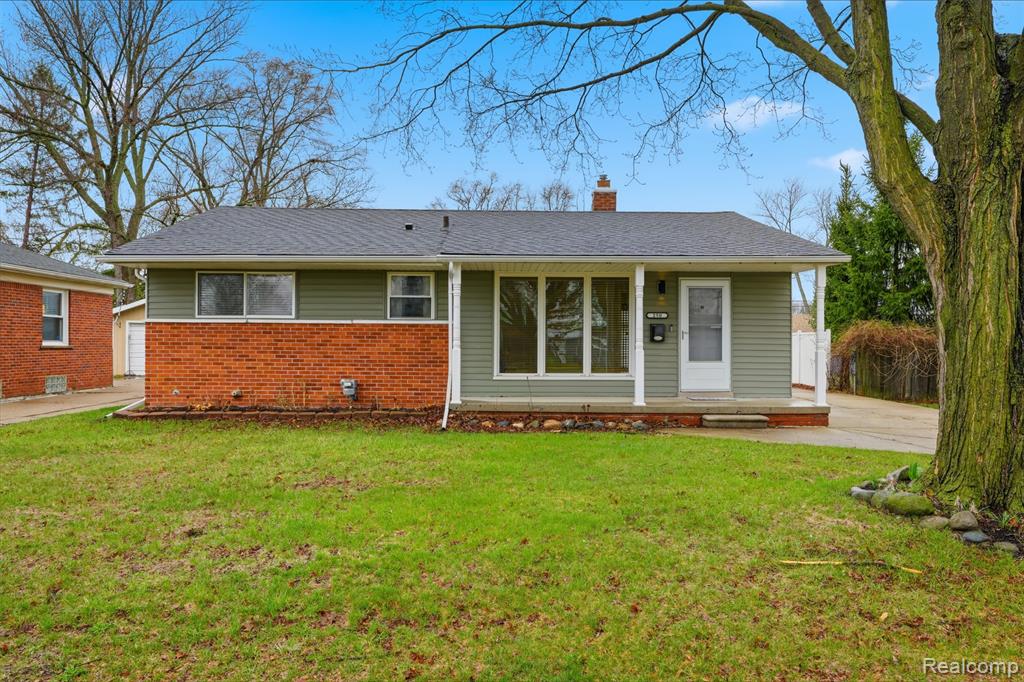 Bungalow featuring a front lawn, brick siding, a chimney, a porch, and a shingled roof