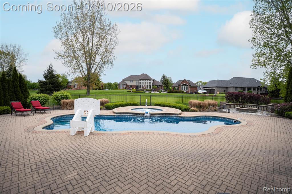 View of pool featuring patio surround, a hot tub, and a residential view