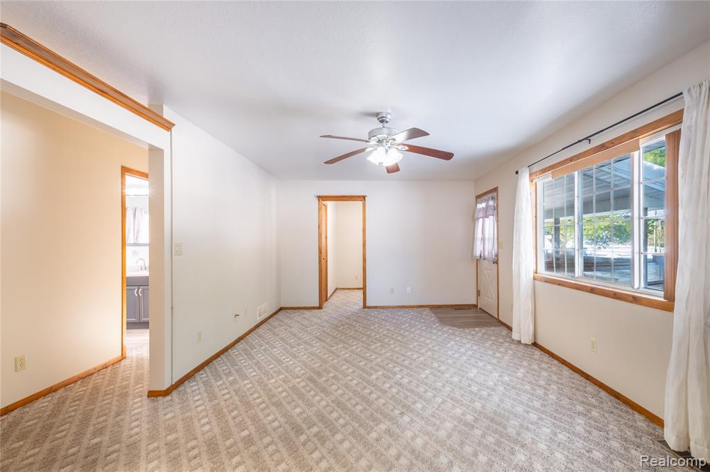 Empty room with light carpet and a ceiling fan