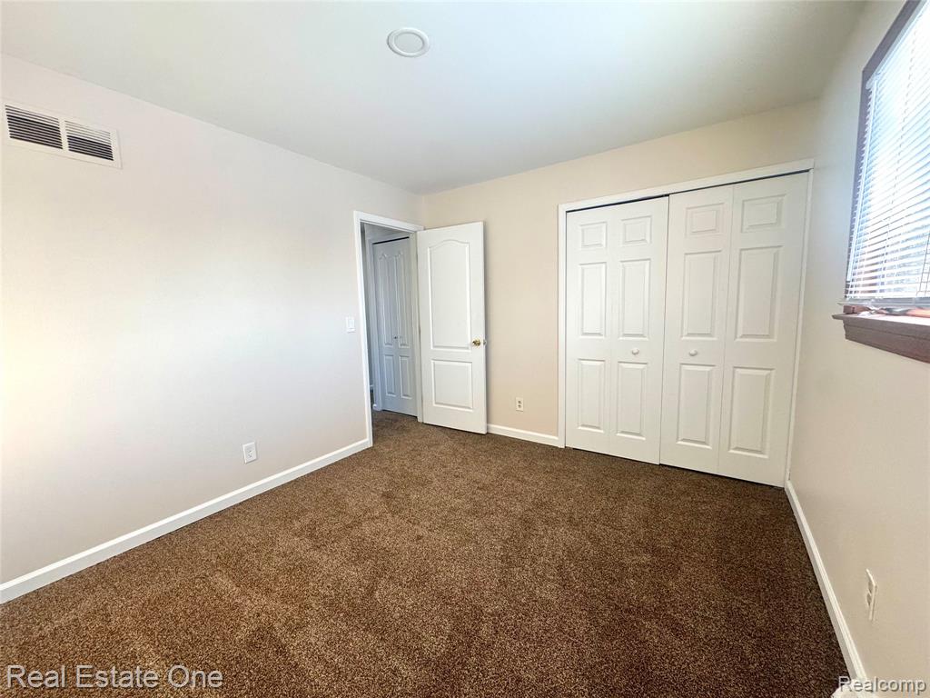 Unfurnished bedroom featuring dark carpet and a closet