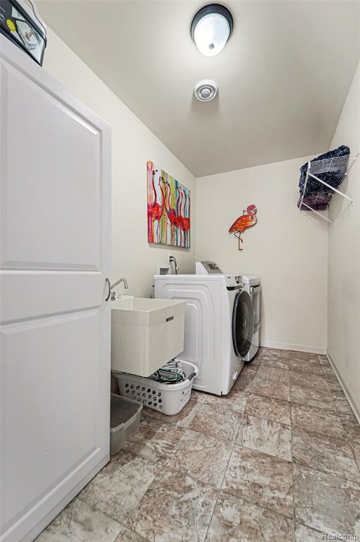 Laundry area featuring separate washer and dryer and light stone finish floors