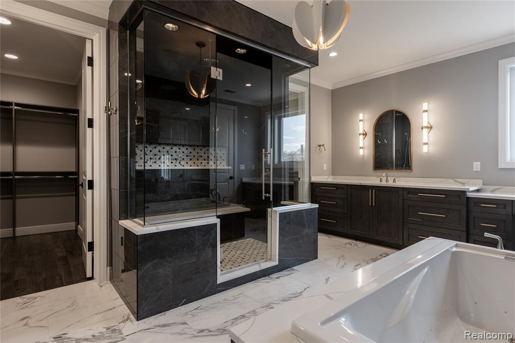Bathroom with crown molding, vanity, a garden tub, a walk in closet, and a shower stall