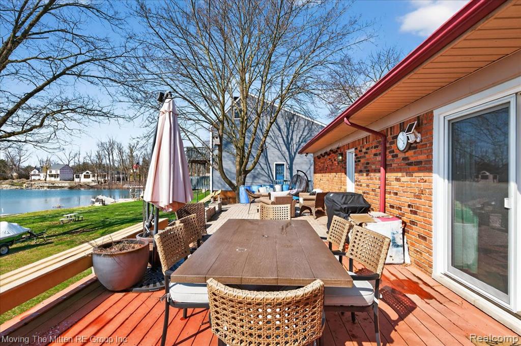 Wooden terrace featuring outdoor lounge area, a water view, and a grill
