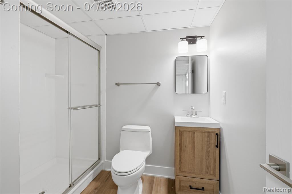 Lower level Bathroom with vanity, a drop ceiling, a shower stall, and laminate floors