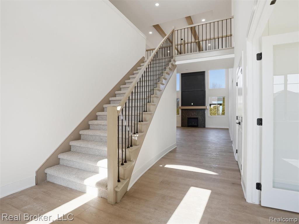 Staircase featuring a fireplace, wood finished floors, a high ceiling, and recessed lighting