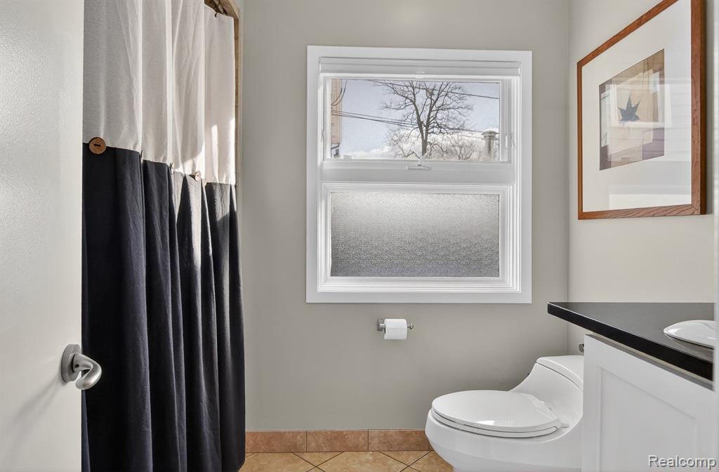 Bathroom featuring curtained shower, vanity, and tile patterned flooring