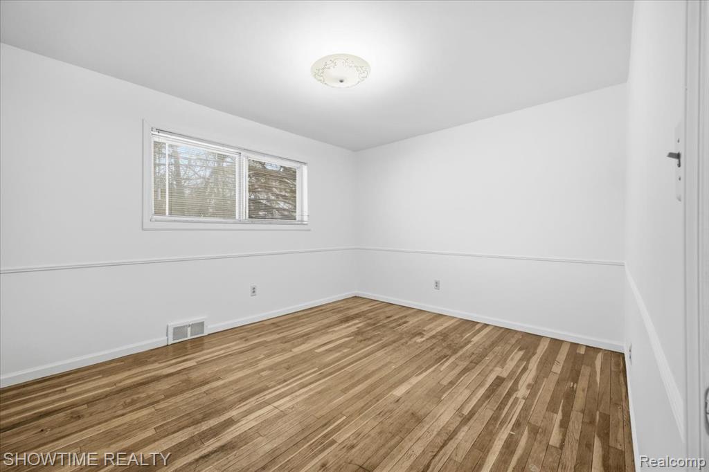 Unfurnished room with hardwood / wood-style flooring and baseboards
