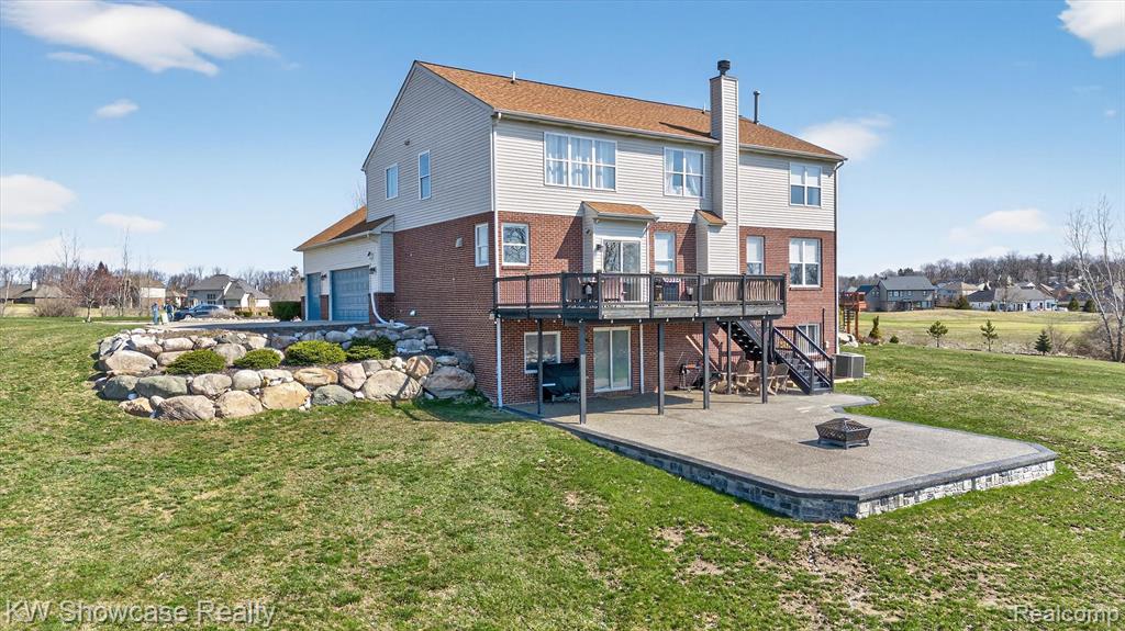 Rear view of house featuring a patio, an outdoor fire pit, a deck, a lawn, and a chimney