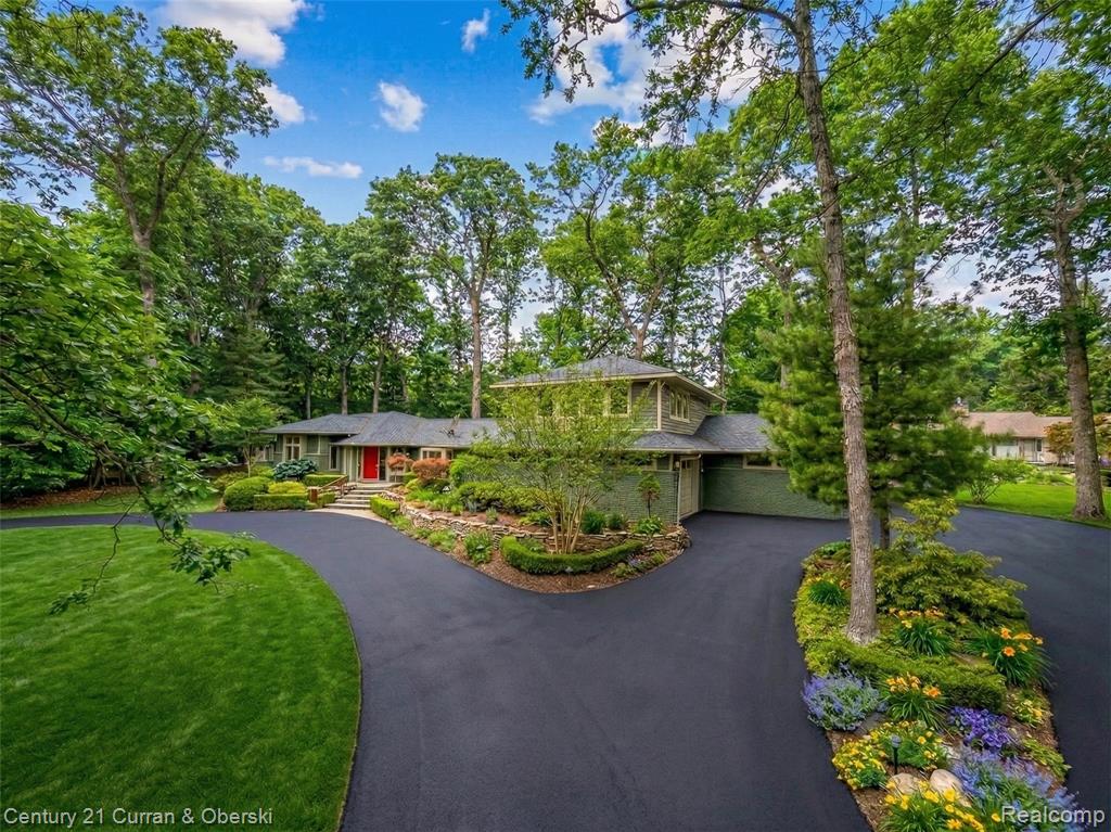 Prairie-style house with driveway, view of wooded area, a garage, and a front yard